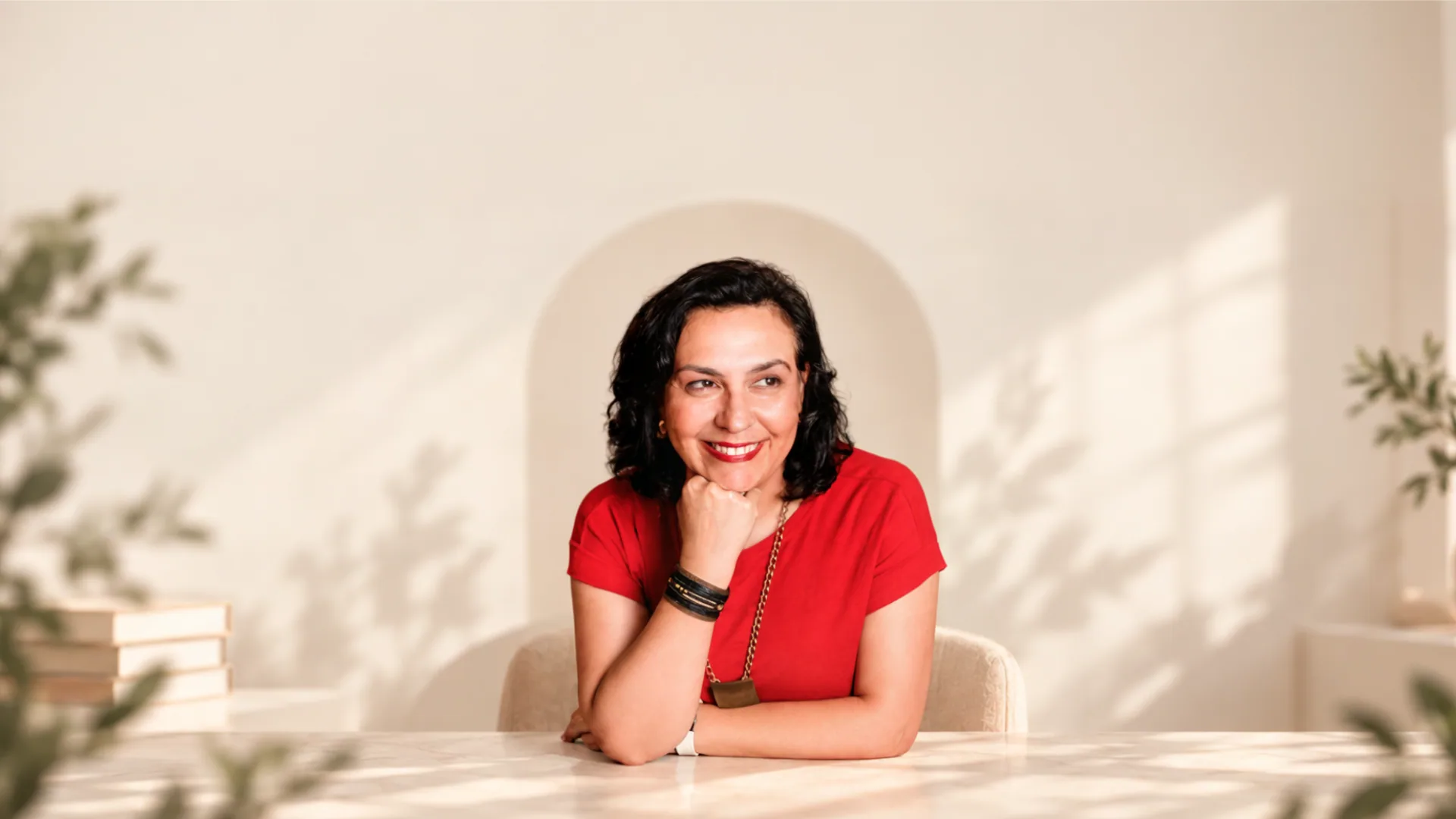 Bel Lindenau sorrindo, com a mão apoiada no queixo